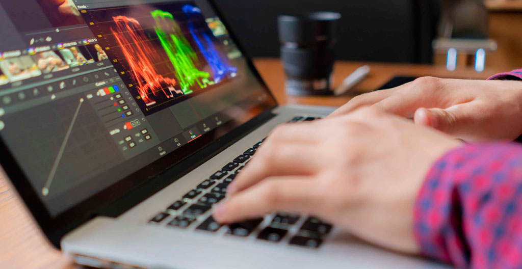 Deux collègues discutent devant un écran d'ordinateur lors d'une session de validation de projet vidéo dans un bureau contemporain